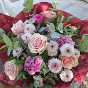 Bouquet di fiori freschi con rose rosa, garofali e margherite, arricchito da rami di eucalipto e confezionato in carta regalo.